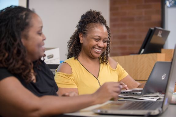 Two women look at laptop computers