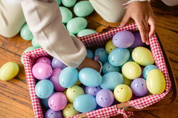 Unrecognizable little girl playing with artificial colorful Easter eggs