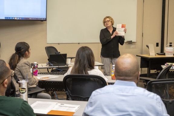Professor in black shirt teaches in front of class
