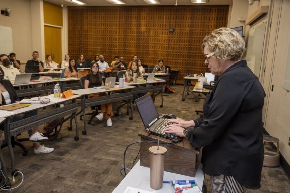 professor in black shirt teaches in front of class