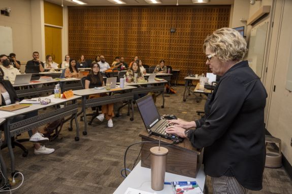 professor in black shirt teaches in front of class 