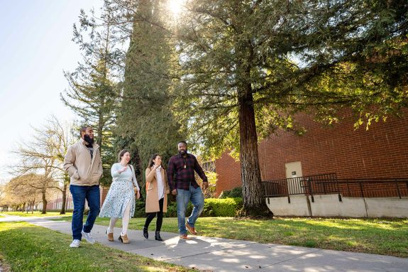 Four people walking on campus