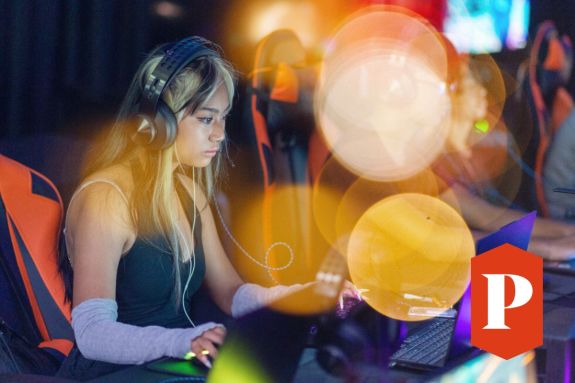 Student playing video games, surrounded by colorful balloons