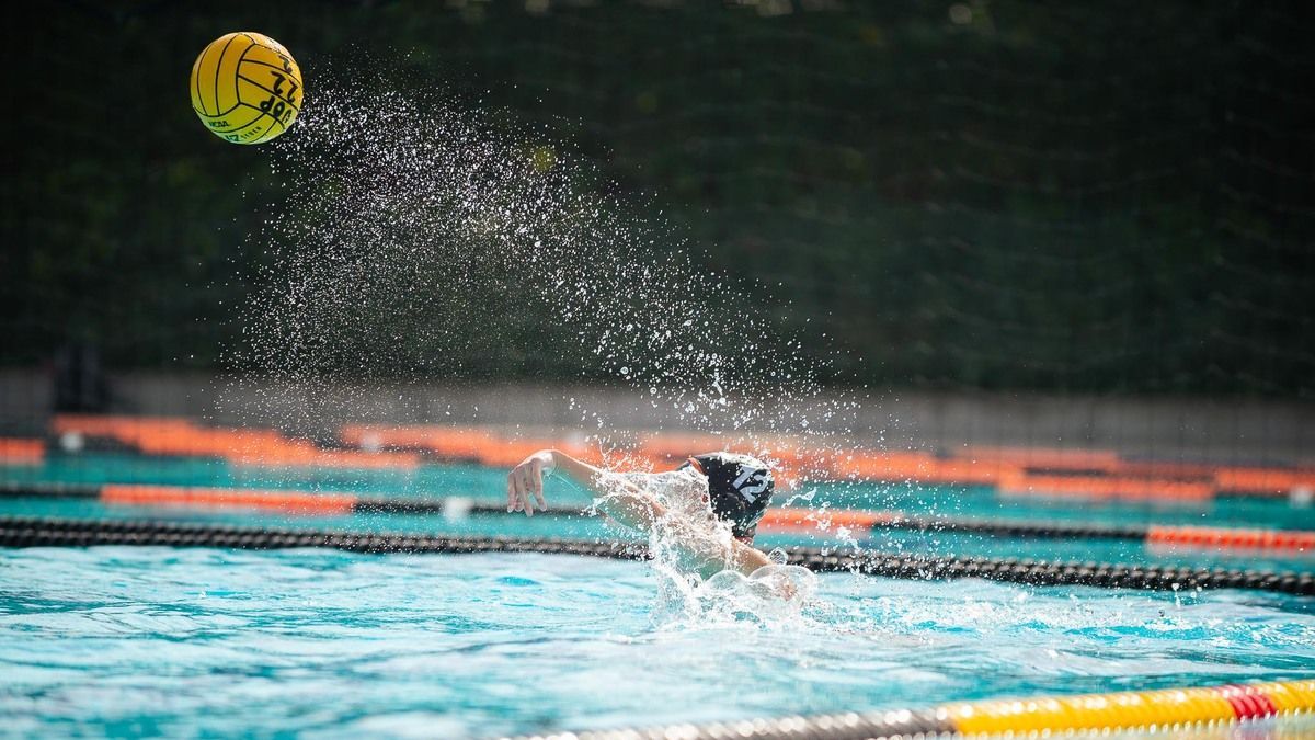 a water polo player throws a ball in the pool