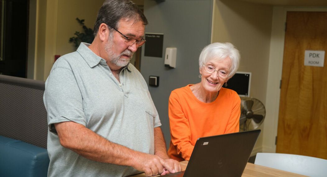 two people look at a laptop